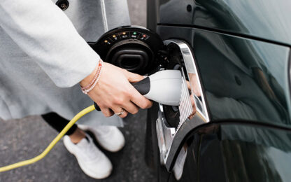 woman's hand plugging in a charging lead to her electric car